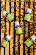 Load image into Gallery viewer, small 100 ml bottles laying on the hive frames with bees around