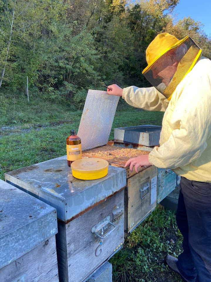 beeekeper inspecting hive with beeelixir at the foreground