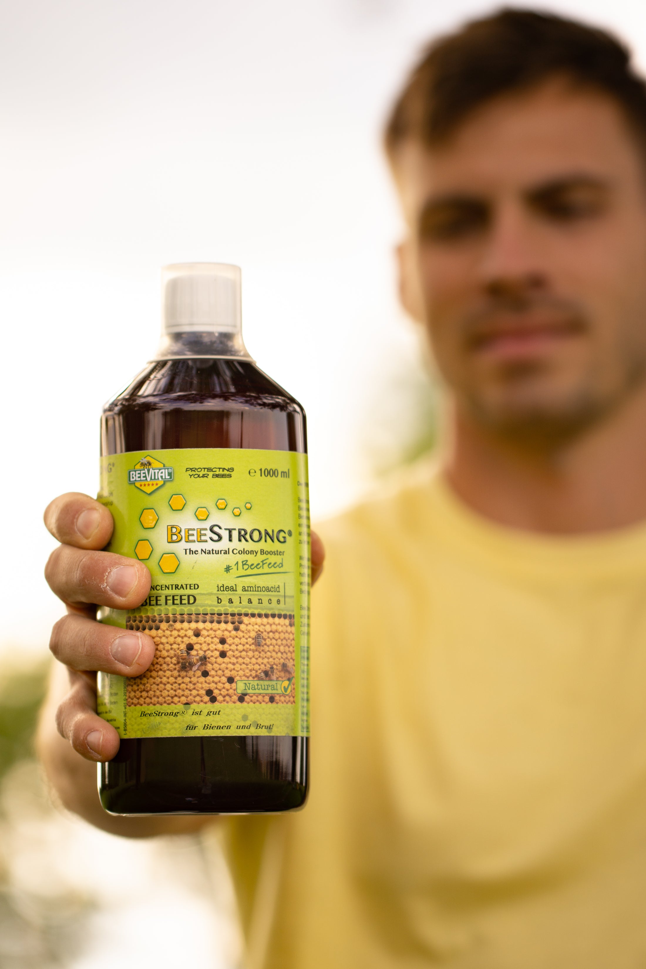 man in diluted background holding 1 litre of beestrong bottle