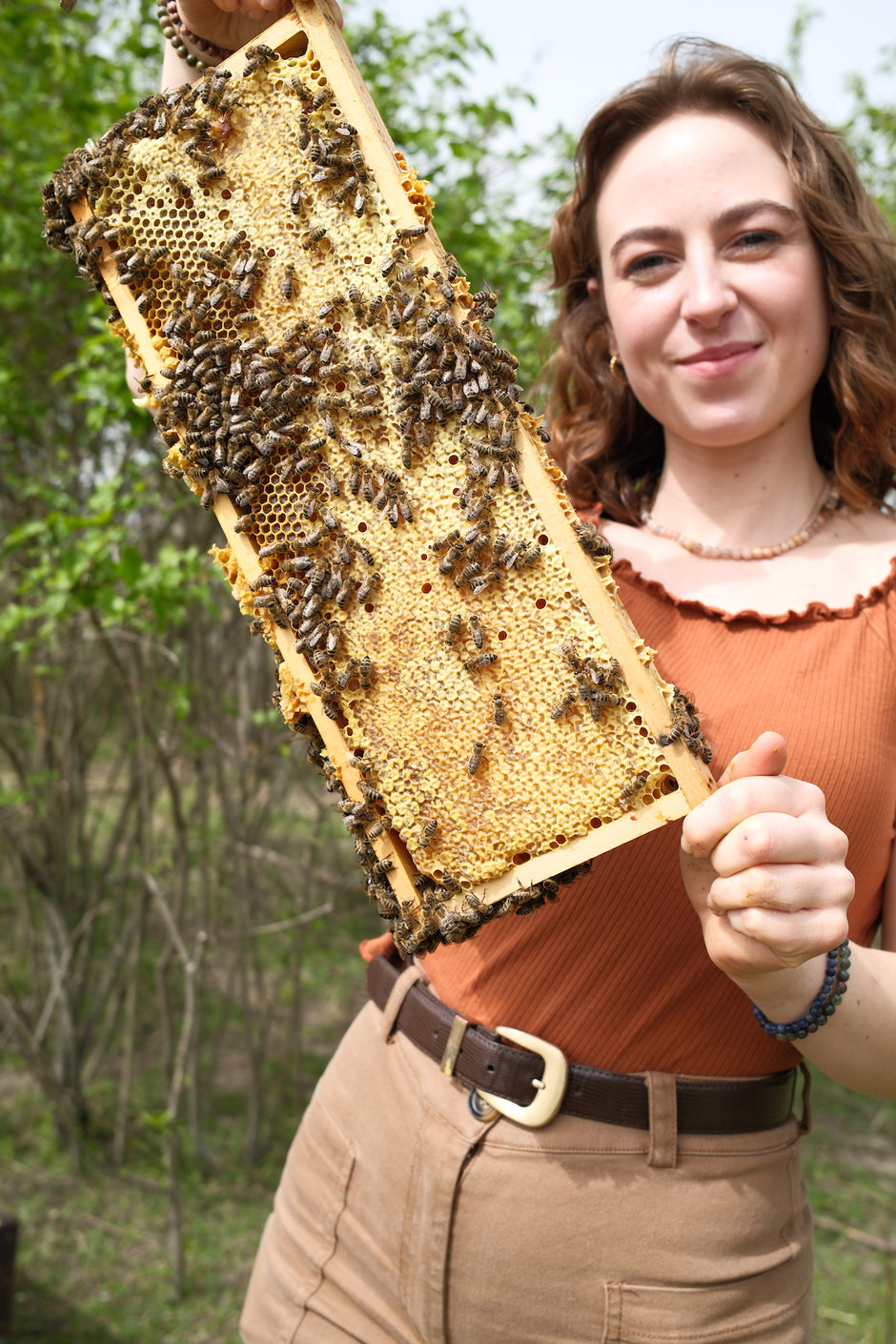 female beekeeper holding well made bee frame with some bees on it